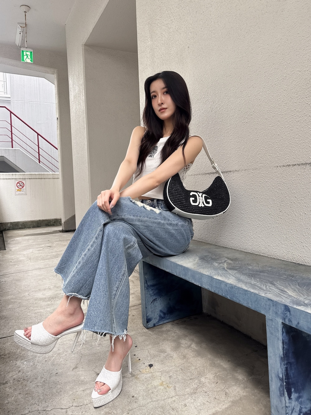 ホワイト系のタンクトップ、ブルー系のデニムパンツ、ホワイト系のパンプスを着用したレディースの夏コーディネートの2枚目の写真