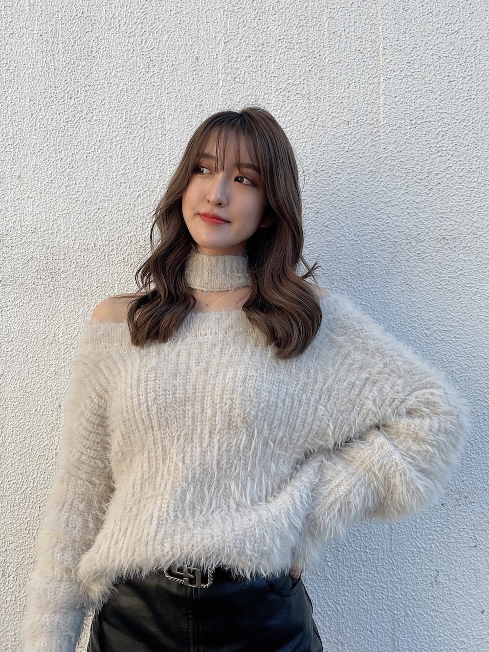 ホワイト系のニット/セーター、ブラック系のスカート、ブラック系のブーツを着用したレディースの冬コーディネートの2枚目の写真