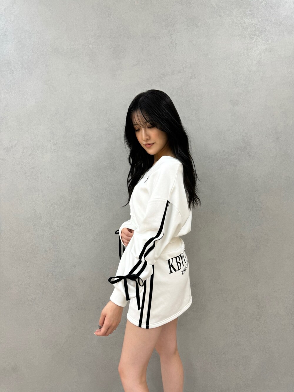 ホワイト系のカーディガン/ボレロ、ホワイト系のスカート、ブラック系のブーツを着用したレディースの秋コーディネートの2枚目の写真