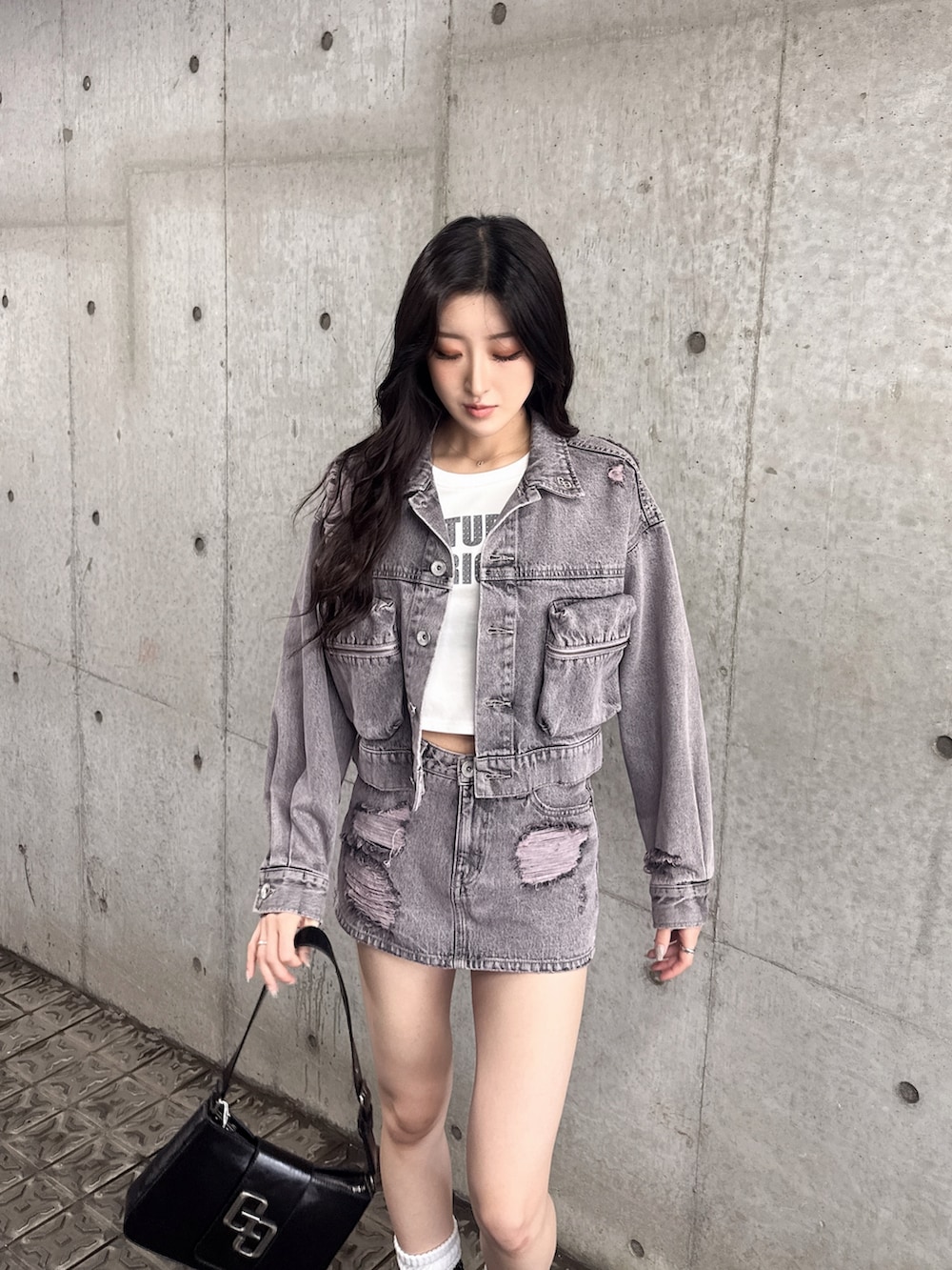 ブラック系のハンドバッグ、ブラック系のブーツ、ピンク系のデニムスカートを着用したレディースの夏コーディネートの2枚目の写真