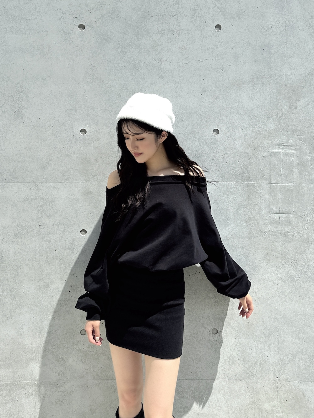 ブラック系のワンピース、ブラック系のブーツ、ホワイト系のニットキャップ/ビーニーを着用したレディースの秋コーディネートの3枚目の写真