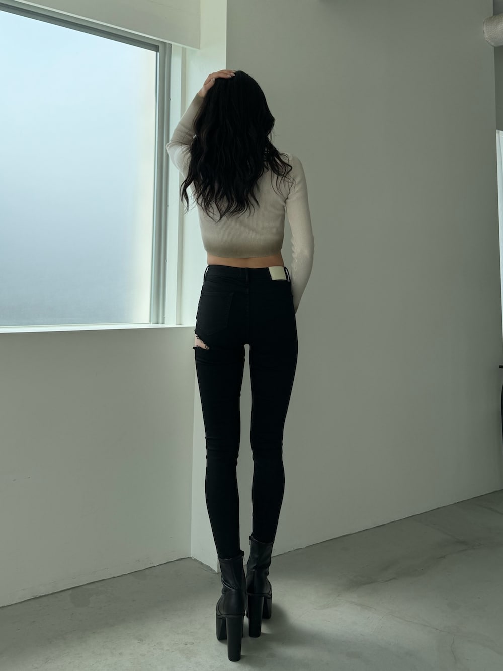 ホワイト系のニット/セーター、ブラック系のデニムパンツ、ブラック系のブーツを着用したレディースの秋コーディネートの2枚目の写真