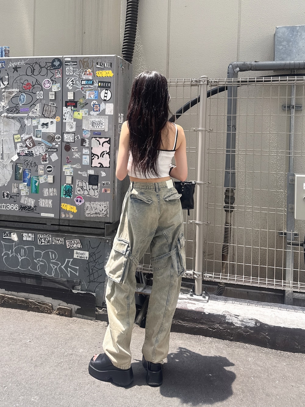 ホワイト系のキャミソール、ブルー系のデニムパンツ、ブラック系のサンダルを着用したレディースの夏コーディネートの2枚目の写真