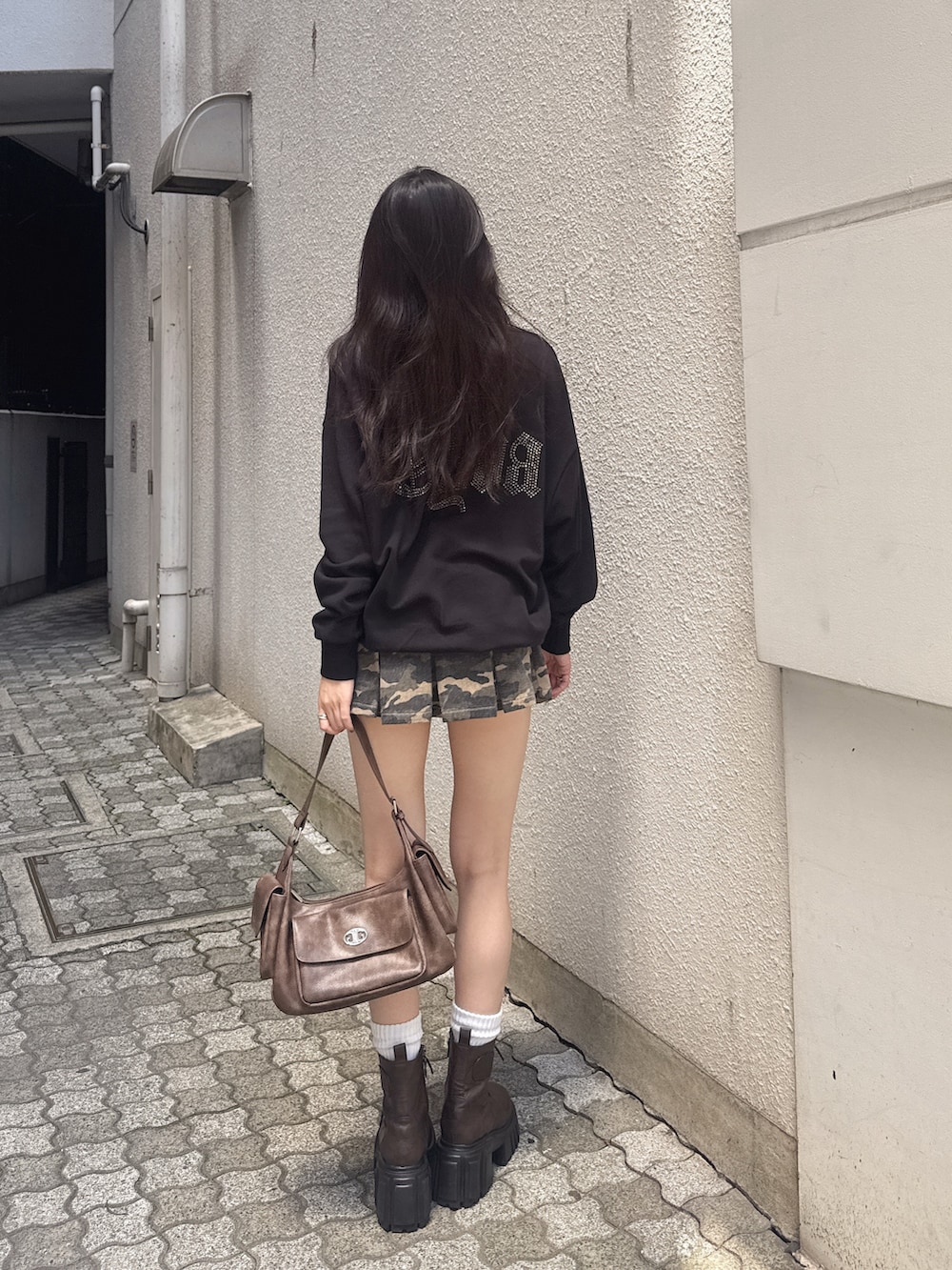 ブラック系のパーカー、その他のデニムスカート、ブラウン系のハンドバッグを着用したレディースの秋コーディネートの4枚目の写真