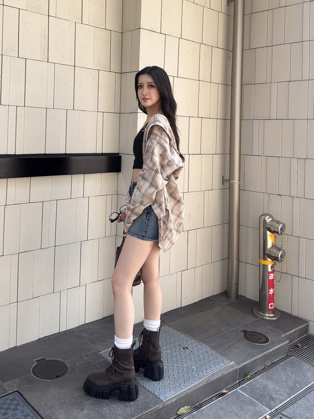 ブルー系のデニムスカート、ブラウン系のハンドバッグ、ベージュ系のシャツ/ブラウスを着用したレディースの夏コーディネートの2枚目の写真