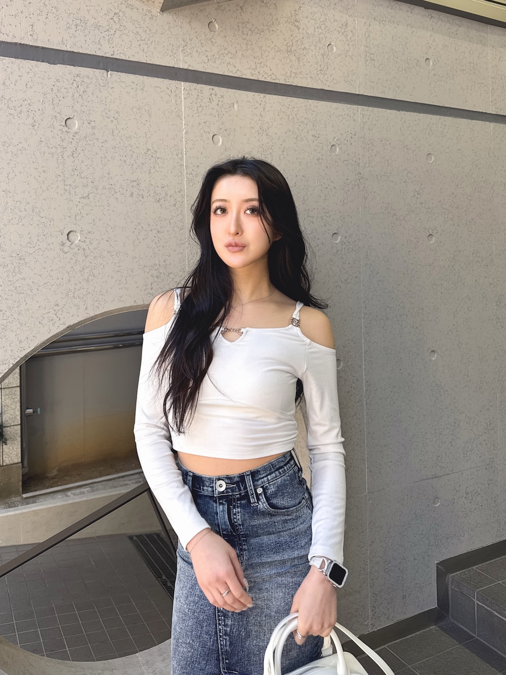 ホワイト系のTシャツ/カットソー、ブルー系のデニムスカート、ホワイト系のハンドバッグを着用したレディースの冬コーディネートの2枚目の写真