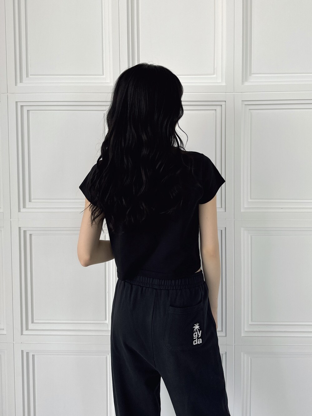 ブラック系のスウェットパンツ、ブラック系のTシャツ/カットソー、ホワイト系のパンプスを着用したレディースの夏コーディネートの4枚目の写真