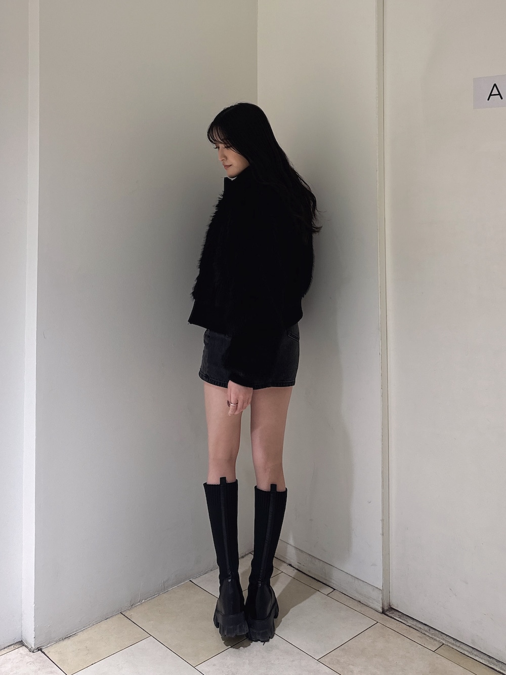 ブラック系のその他アウター、ブラック系のニット/セーター、ブラック系のデニムスカートを着用したレディースの秋コーディネートの2枚目の写真