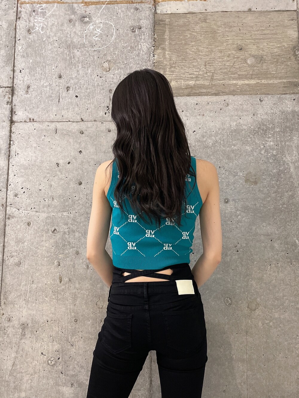 グリーン系のニット/セーター、ブラック系のデニムパンツ、ブラック系のサンダルを着用したレディースの春コーディネートの4枚目の写真