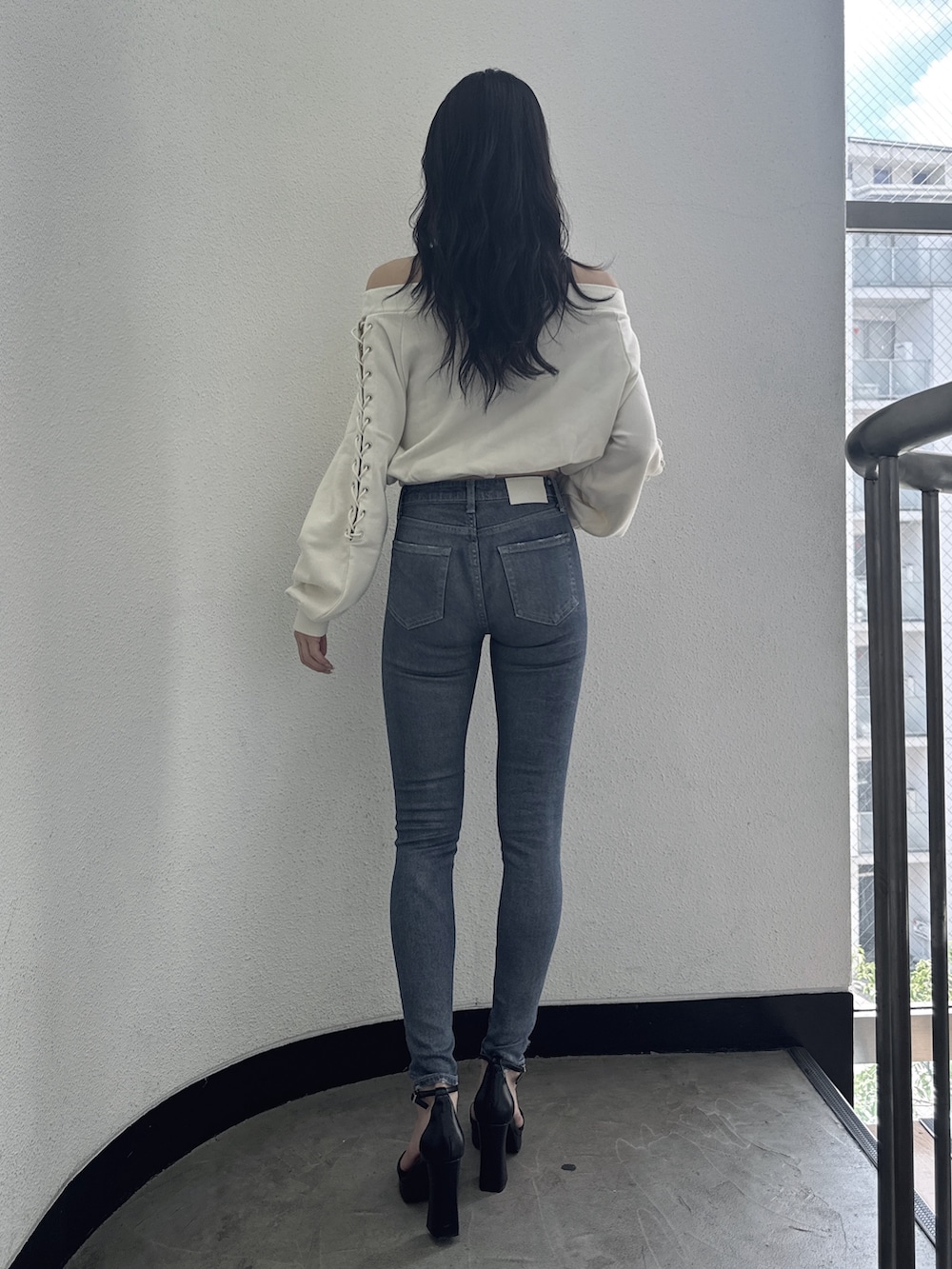 ホワイト系のスウェット、ブルー系のデニムパンツ、ブラック系のサンダルを着用したレディースの夏コーディネートの2枚目の写真