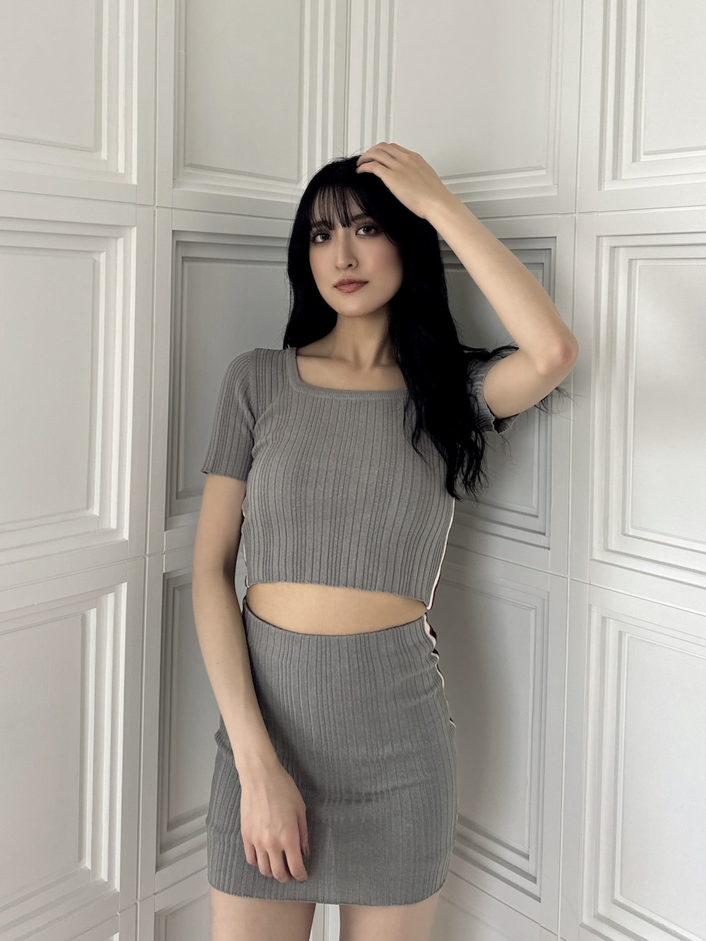 グレー系のニット/セーター、グレー系のスカート、ブラック系のサンダルを着用したレディースの夏コーディネートの5枚目の写真