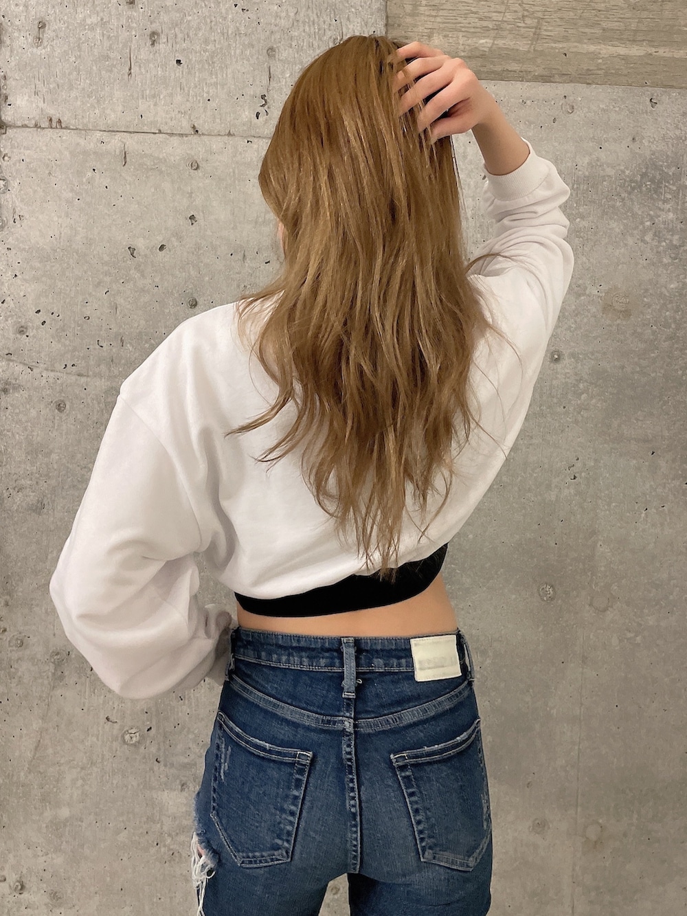 ホワイト系のスウェット、ブルー系のデニムパンツ、ホワイト系のスニーカーを着用したレディースの冬コーディネートの3枚目の写真