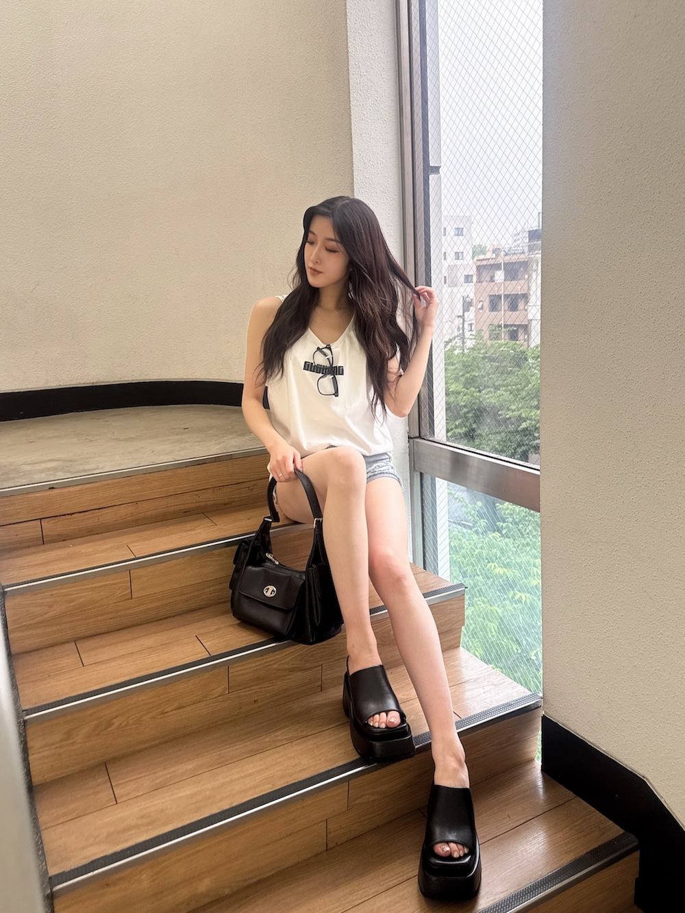 ホワイト系のワンピース、ブルー系のデニムパンツ、ブラック系のハンドバッグを着用したレディースの夏コーディネートの2枚目の写真