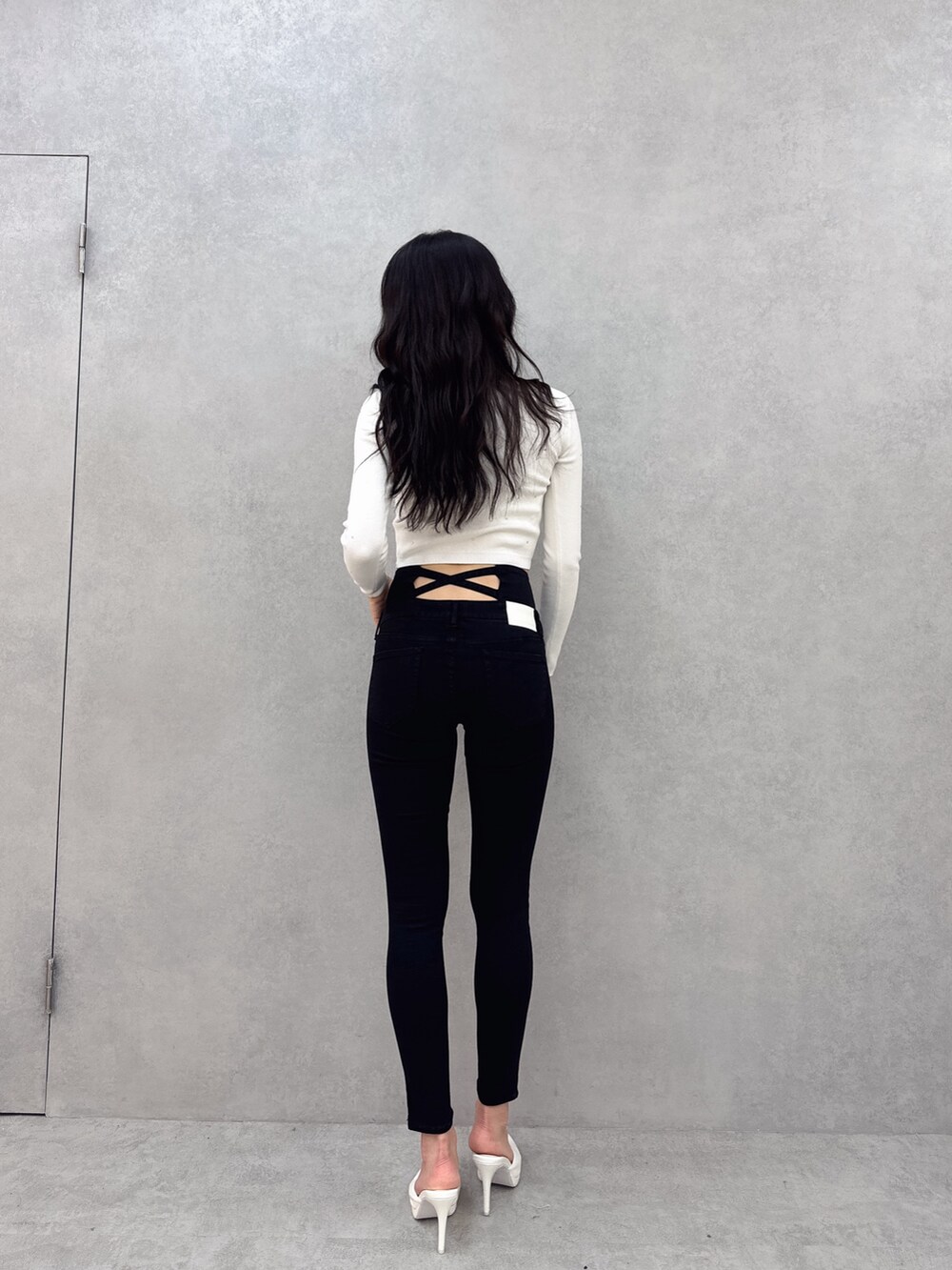 ホワイト系のニット/セーター、ブラック系のデニムパンツ、ホワイト系のパンプスを着用したレディースの冬コーディネートの2枚目の写真