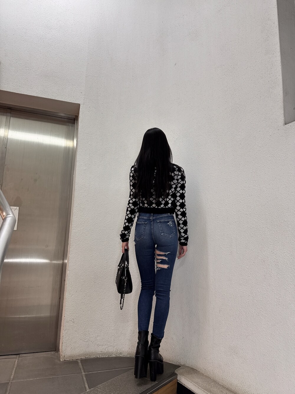 ブラック系のキャミソール、ブラック系のカーディガン/ボレロ、ブルー系のデニムパンツを着用したレディースの冬コーディネートの2枚目の写真