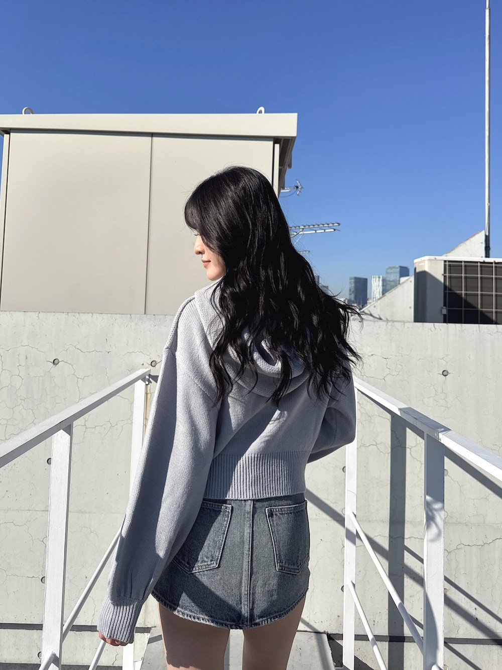 グレー系のニット/セーター、ブルー系のデニムスカート、ブラック系のブーツを着用したレディースの冬コーディネートの4枚目の写真