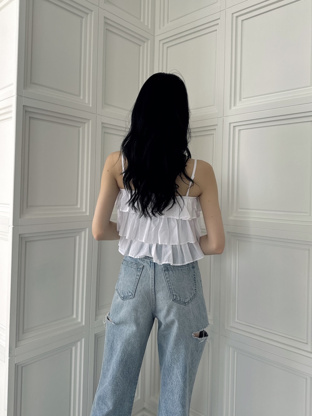 ホワイト系のキャミソール、ブルー系のデニムパンツ、ホワイト系のサンダルを着用したレディースの夏コーディネートの4枚目の写真