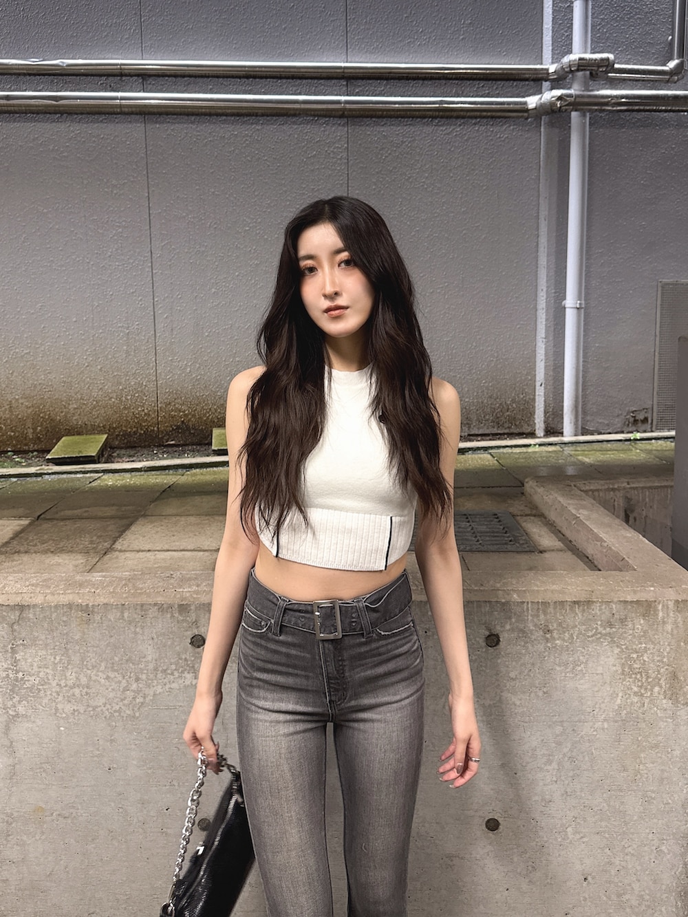 ホワイト系のニット/セーター、ブラック系のデニムパンツ、ブラック系のサンダルを着用したレディースの夏コーディネートの3枚目の写真