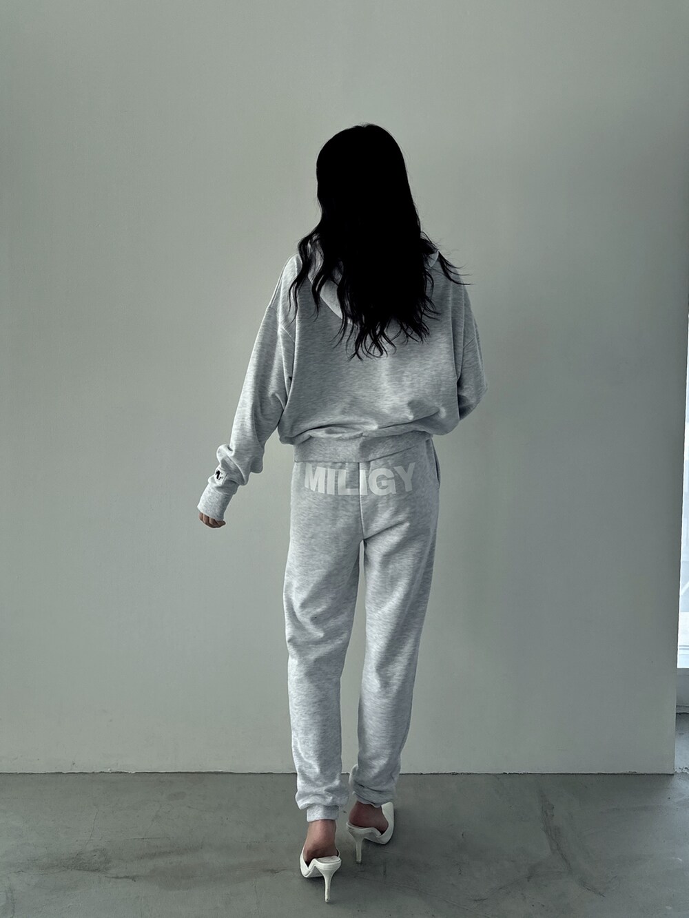 グレー系のパーカー、グレー系のスウェットパンツ、ホワイト系のパンプスを着用したレディースの秋コーディネートの2枚目の写真