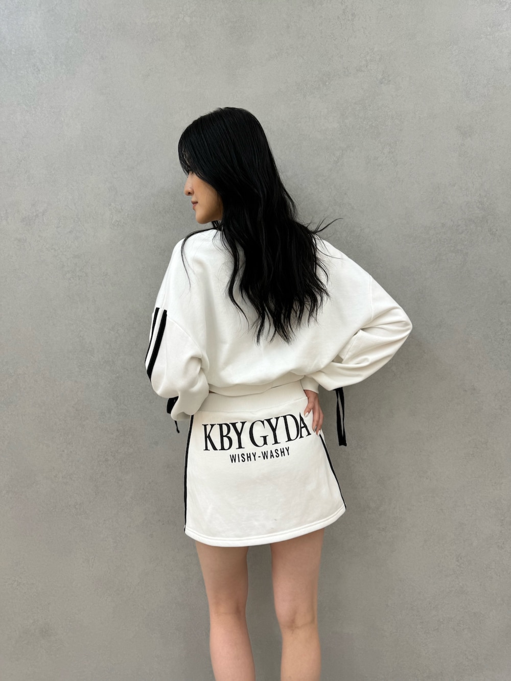 ホワイト系のカーディガン/ボレロ、ホワイト系のスカート、ブラック系のブーツを着用したレディースの秋コーディネートの3枚目の写真