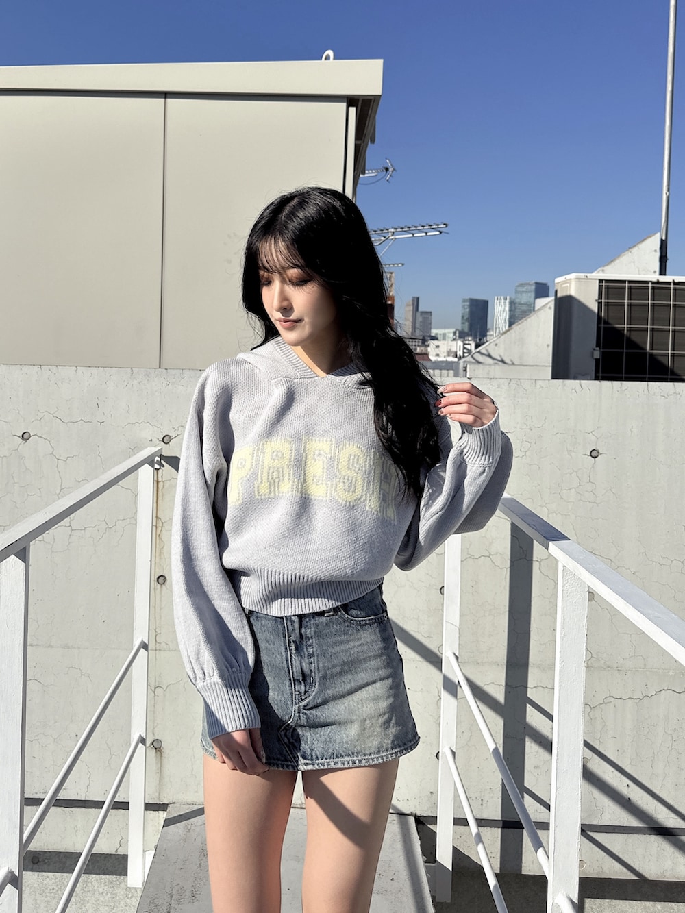 グレー系のニット/セーター、ブルー系のデニムスカート、ブラック系のブーツを着用したレディースの冬コーディネートの2枚目の写真