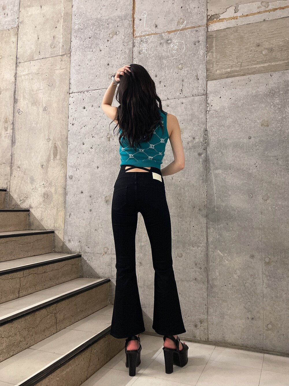 グリーン系のニット/セーター、ブラック系のデニムパンツ、ブラック系のサンダルを着用したレディースの春コーディネートの3枚目の写真