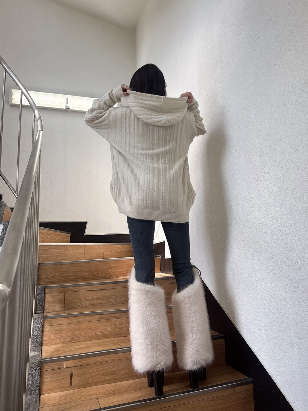 ホワイト系のワンピース、ブルー系のデニムパンツ、ブラック系のブーツを着用したレディースの秋コーディネートの2枚目の写真