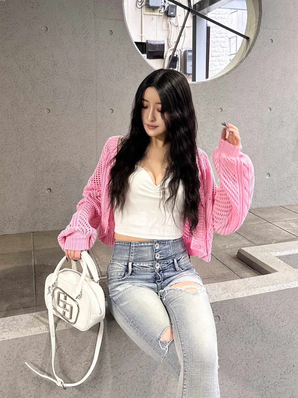 ピンク系のニット/セーター、ホワイト系のキャミソール、ブルー系のデニムパンツを着用したレディースの春コーディネートの2枚目の写真