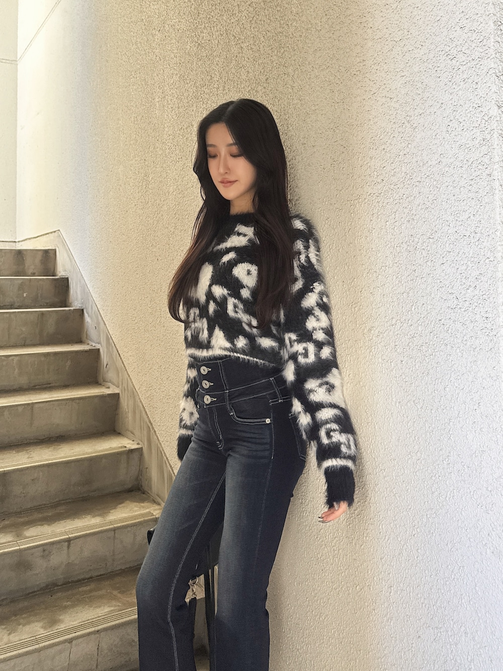 ブルー系のデニムパンツ、ブラック系のニット/セーター、ブラック系のブーツを着用したレディースの冬コーディネートの3枚目の写真