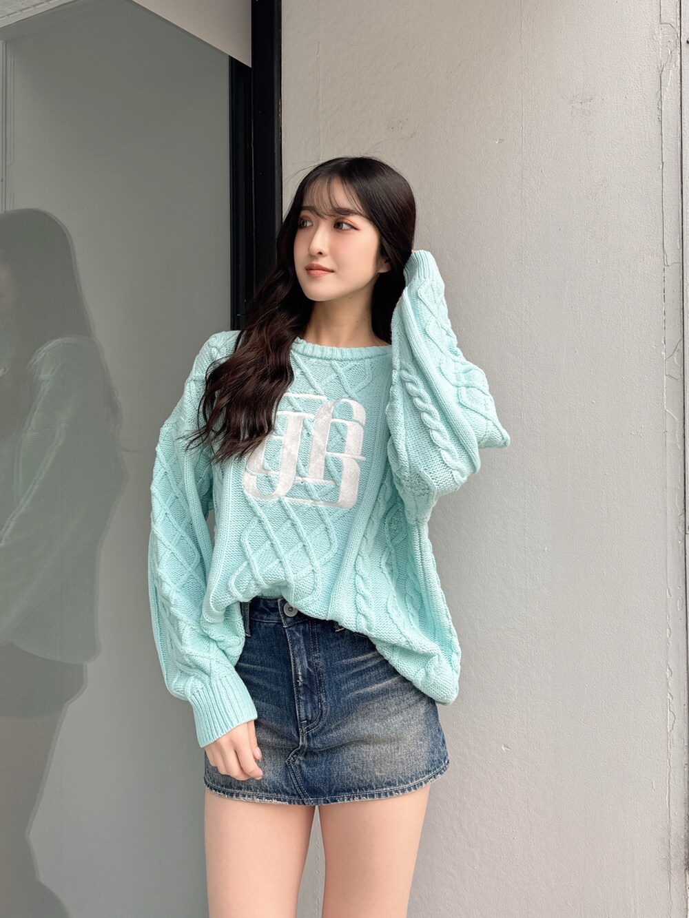 グリーン系のニット/セーター、ブルー系のデニムスカートを着用したレディースの冬コーディネートの3枚目の写真