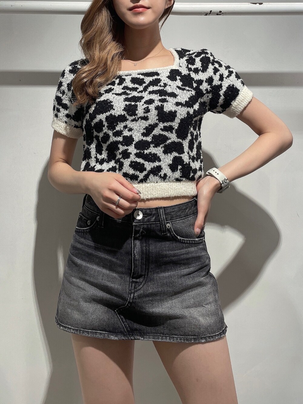 ホワイト系のニット/セーター、ブラック系のデニムスカート、ブラック系のブーツを着用したレディースの夏コーディネートの5枚目の写真