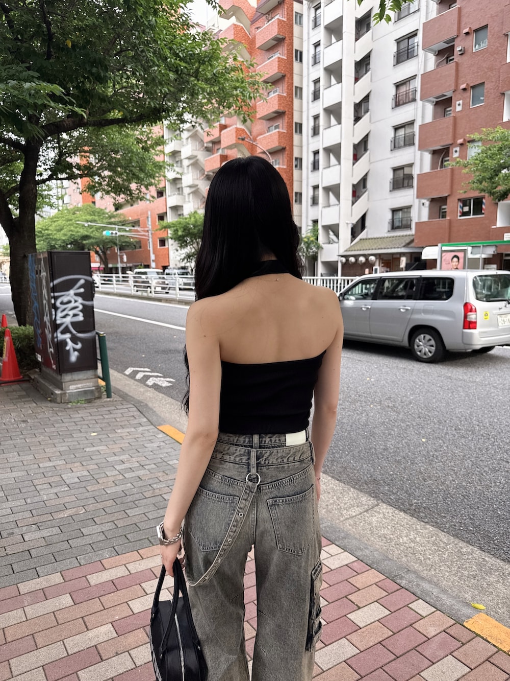 ブルー系のデニムパンツ、ブラック系のキャミソール、ブラック系のスニーカーを着用したレディースの夏コーディネートの5枚目の写真