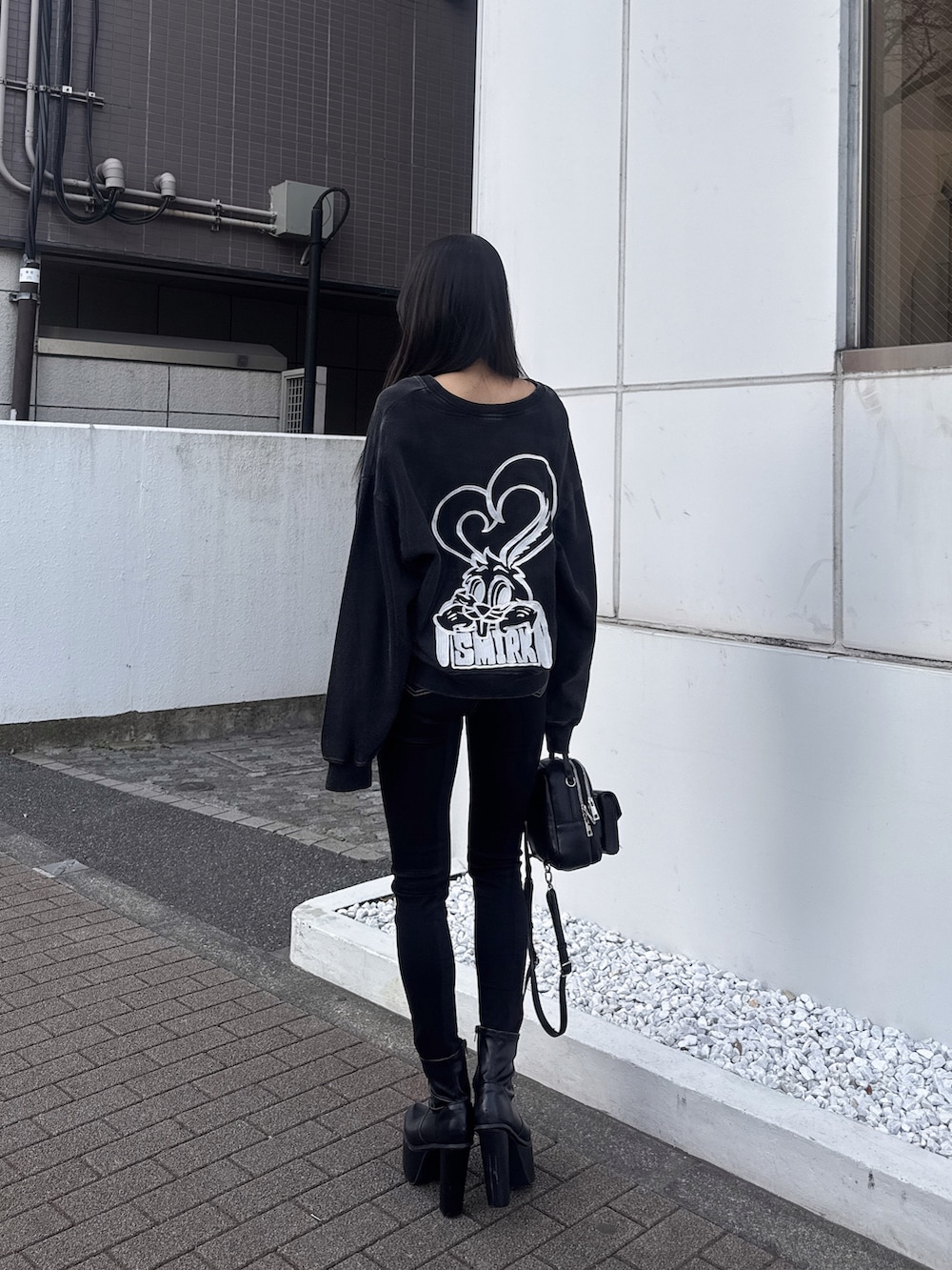 ブラック系のスウェット、ブラック系のデニムパンツ、ブラック系のブーツを着用したレディースの冬コーディネートの2枚目の写真