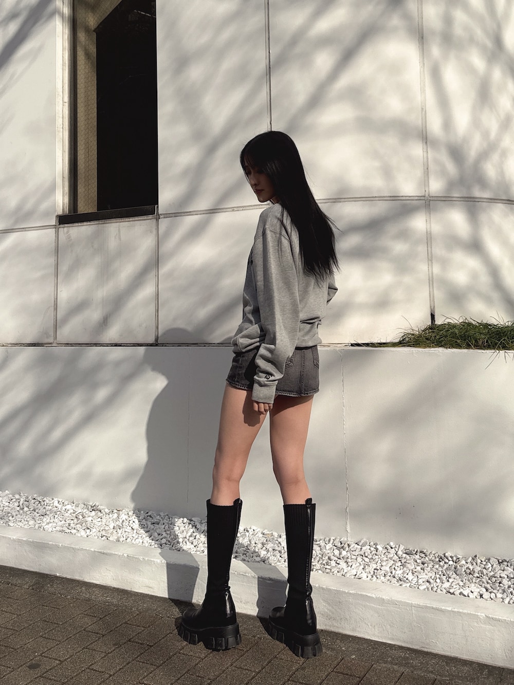 グレー系のスウェット、ブラック系のデニムスカート、ブラック系のブーツを着用したレディースの冬コーディネートの3枚目の写真