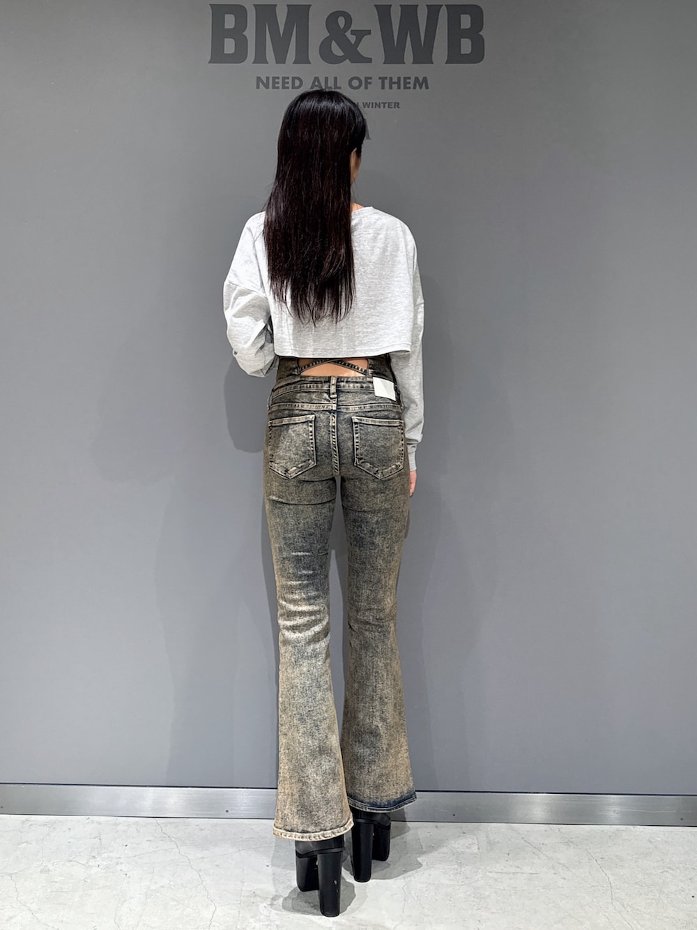 グレー系のTシャツ/カットソー、ブルー系のデニムパンツ、ブラック系のブーツを着用したレディースの秋コーディネートの2枚目の写真