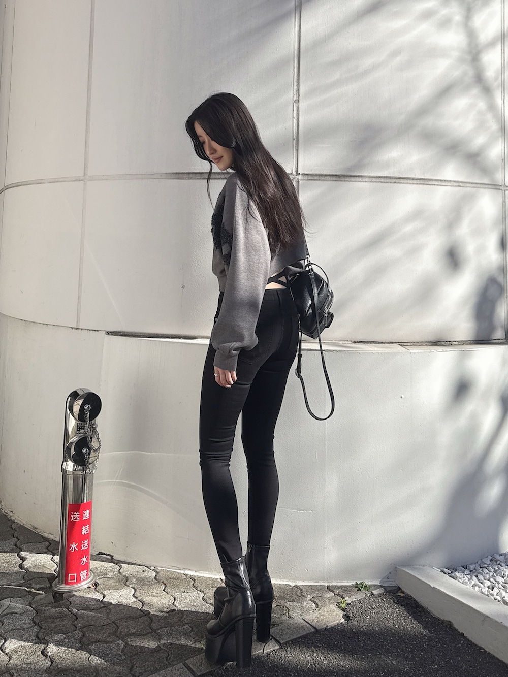 ブラック系のデニムパンツ、ブラック系のブーツ、グレー系のニット/セーターを着用したレディースの冬コーディネートの4枚目の写真