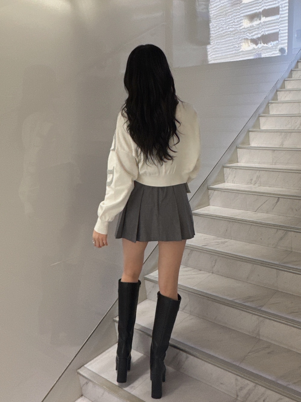 ホワイト系のニット/セーター、グレー系のスカート、ブラック系のブーツを着用したレディースの冬コーディネートの3枚目の写真