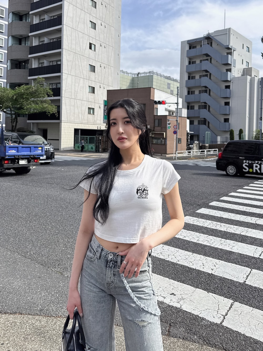 ホワイト系のTシャツ/カットソー、ブルー系のデニムパンツ、ブラック系のスニーカーを着用したレディースの春コーディネートの2枚目の写真