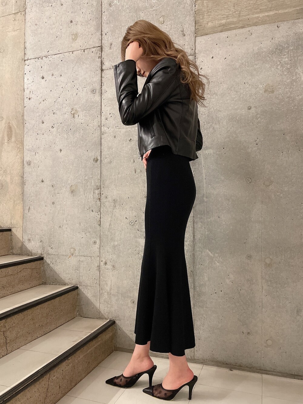 ブラック系のニット/セーター、ブラック系のスカート、ブラック系のライダースジャケットを着用したレディースの冬コーディネートの2枚目の写真