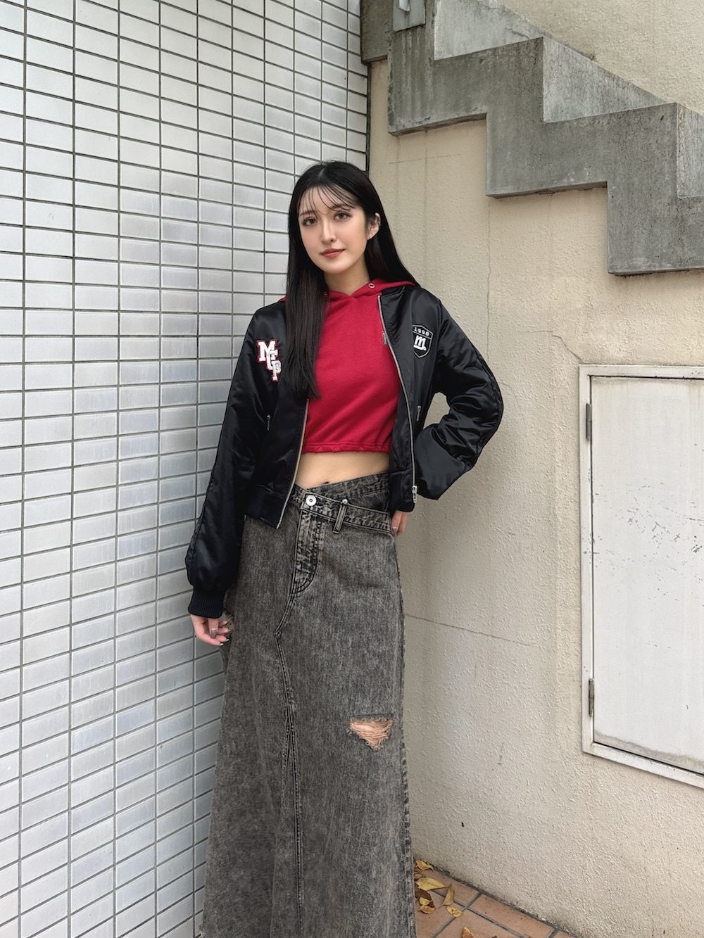 ブラック系のブルゾン、レッド系のパーカー、ブラック系のデニムスカートを着用したレディースの秋コーディネートの3枚目の写真