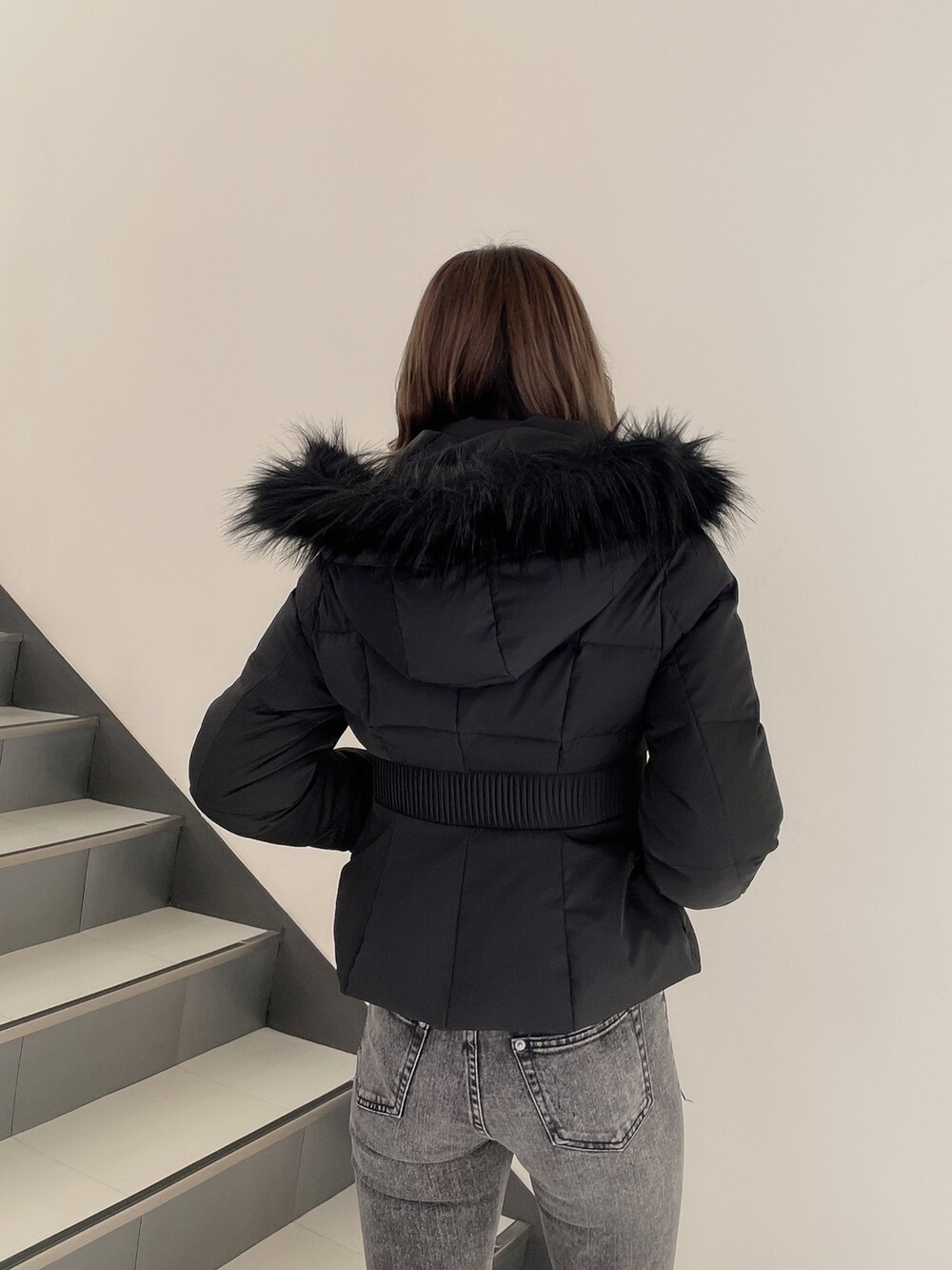 ブラック系のデニムパンツ、ホワイト系のパンプス、ブラック系のその他アウターを着用したレディースの冬コーディネートの2枚目の写真