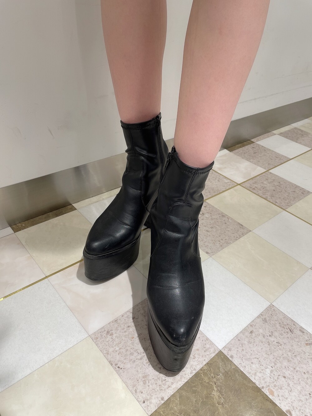 グレー系のワンピース、ブラック系のデニムパンツ、ブラック系のブーツを着用したレディースの冬コーディネートの6枚目の写真