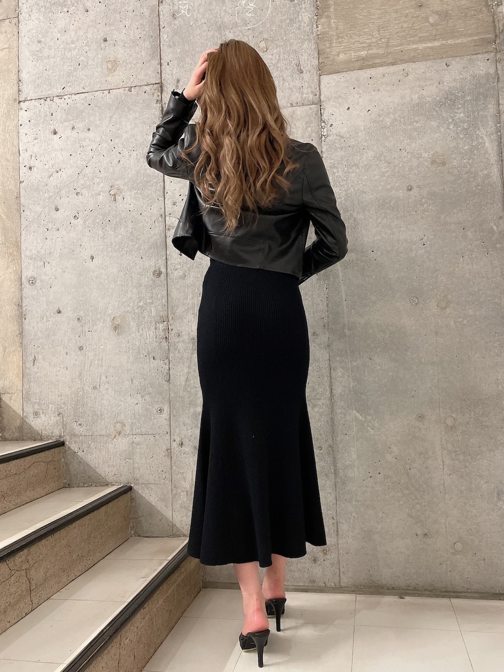 ブラック系のニット/セーター、ブラック系のスカート、ブラック系のライダースジャケットを着用したレディースの冬コーディネートの3枚目の写真