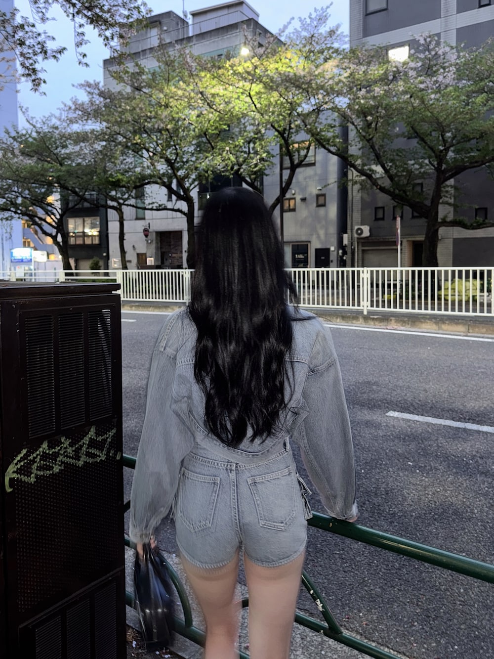 ブルー系のデニムジャケット、ブルー系のデニムパンツ、ブラック系のハンドバッグを着用したレディースの春コーディネートの6枚目の写真