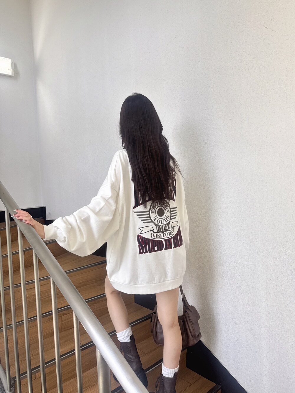 ホワイト系のスウェット、ブルー系のデニムスカート、ブラウン系のブーツを着用したレディースの夏コーディネートの2枚目の写真