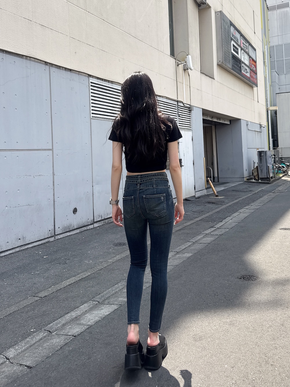 ブラック系のTシャツ/カットソー、ブルー系のデニムパンツ、ブラック系のサンダルを着用したレディースの春コーディネートの3枚目の写真