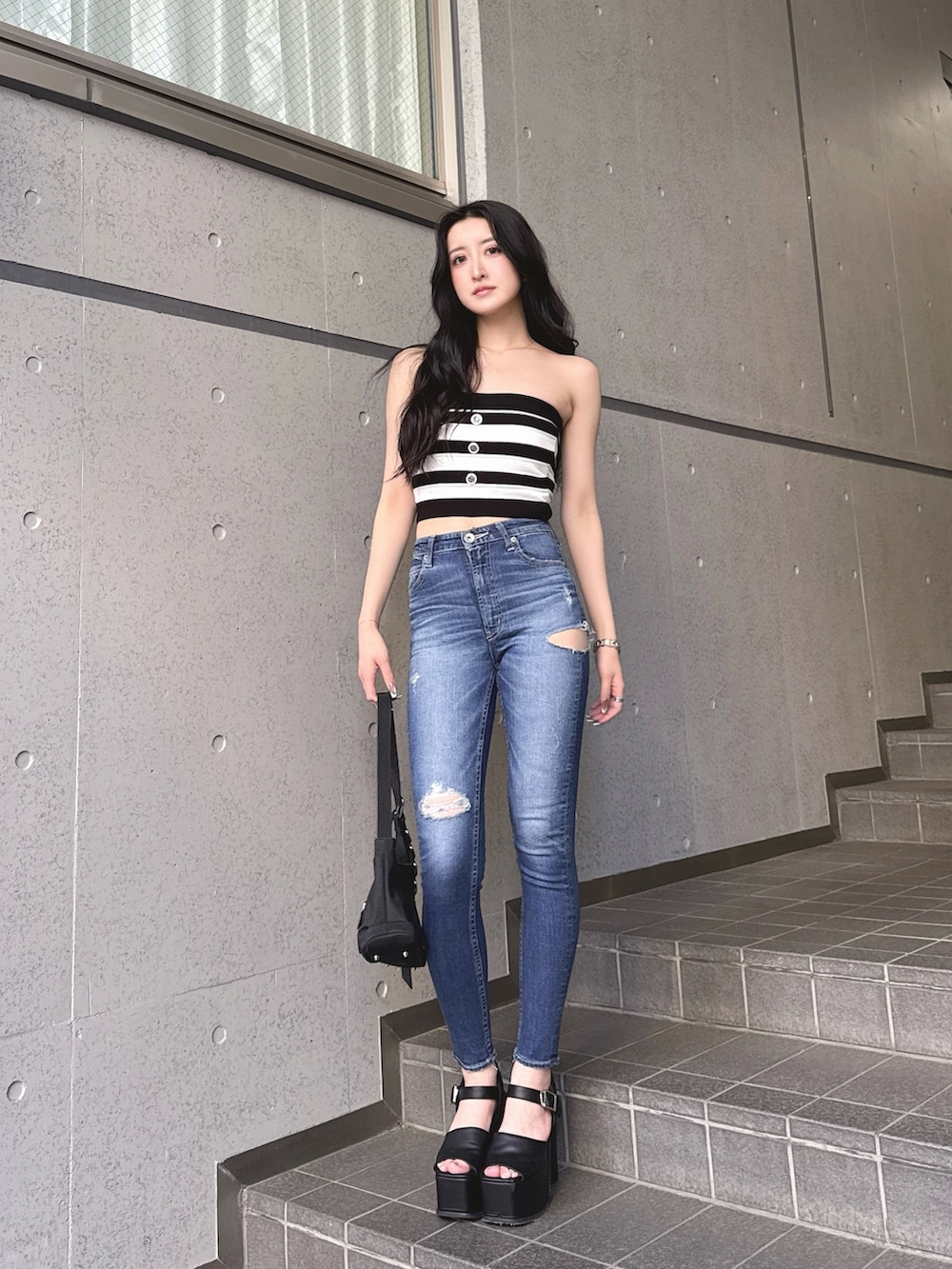 ブラック系のニット/セーター、ブルー系のデニムパンツ、ブラック系のサンダルを着用したレディースの春コーディネートの2枚目の写真
