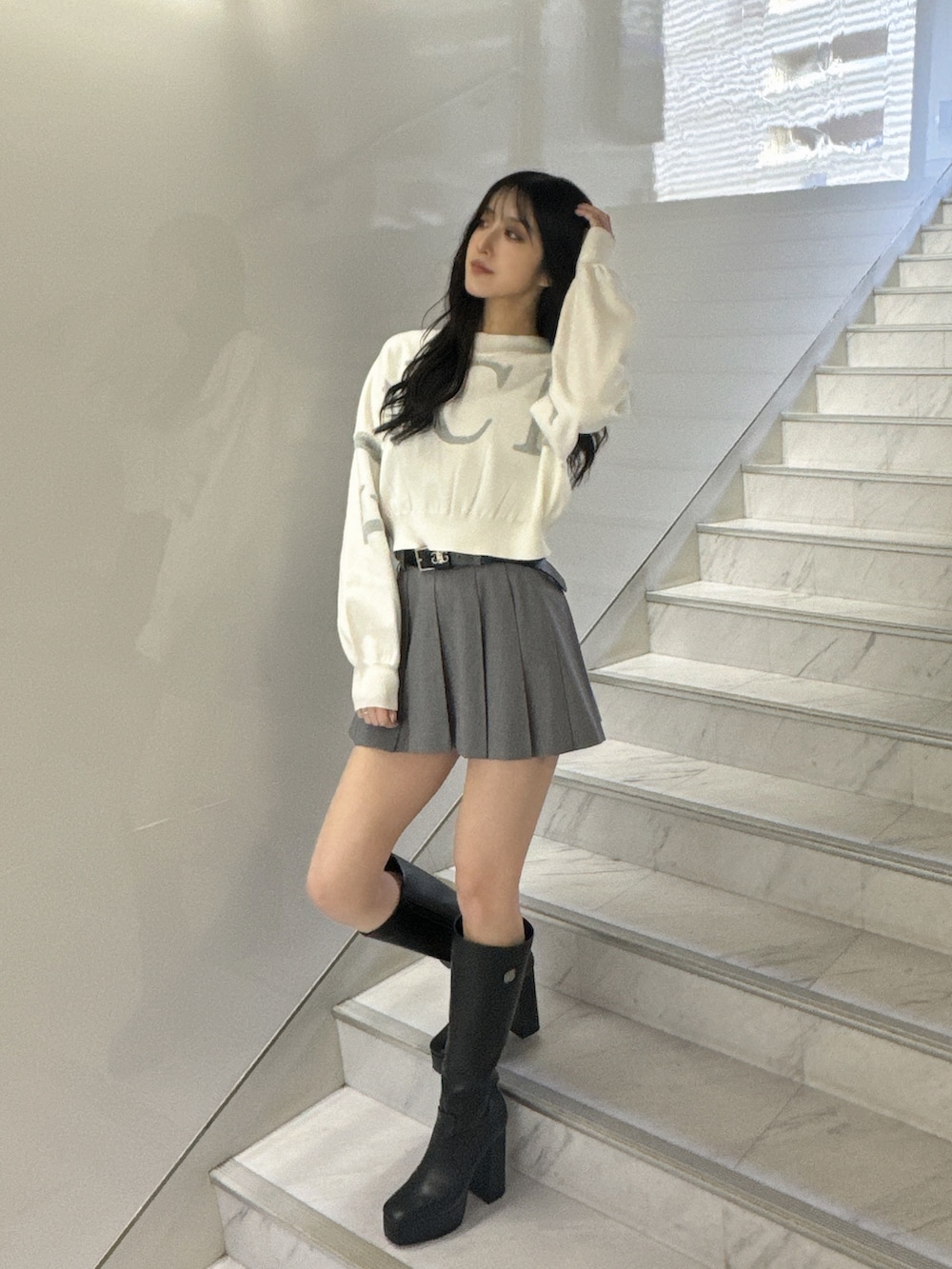 ホワイト系のニット/セーター、グレー系のスカート、ブラック系のブーツを着用したレディースの冬コーディネートの2枚目の写真