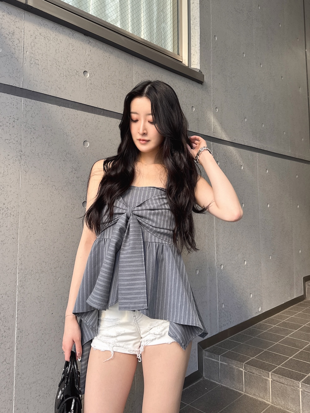 グレー系のキャミソール、ブラック系のサンダル、ホワイト系のデニムパンツを着用したレディースの春コーディネートの3枚目の写真