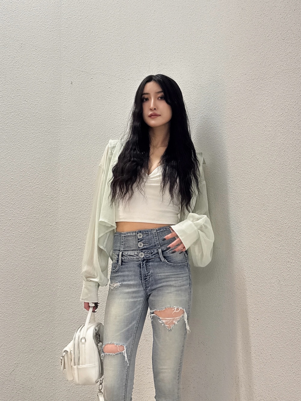 グリーン系のシャツ/ブラウス、ホワイト系のキャミソール、ブルー系のデニムパンツを着用したレディースの春コーディネートの3枚目の写真